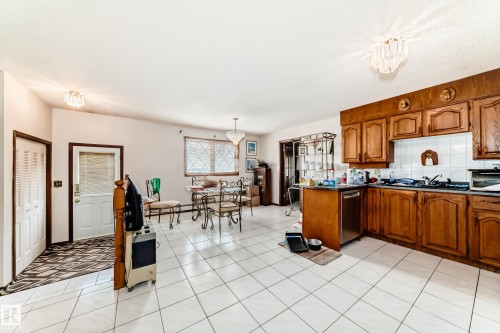 Kitchen featuring wood cabinetry, white tile backsplash, and an integrated stainless steel dishwasher - 208 Willow Crescent, Wetaskiwin, AB - Indoor Photo Showing Kitchen