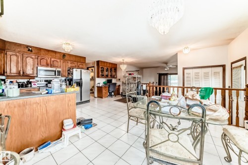 Kitchen and dining area featuring wood cabinetry, stainless steel appliances, and white tile flooring - 208 Willow Crescent, Wetaskiwin, AB - Indoor Photo Showing Kitchen