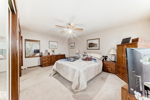 Carpeted room featuring a ceiling fan with integrated lighting, white walls, and built-in closet with wood-finish doors - 208 Willow Crescent, Wetaskiwin, AB - Indoor Photo Showing Bedroom