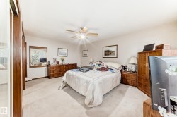 Carpeted room featuring a ceiling fan with integrated lighting, white walls, and built-in closet with wood-finish doors - 