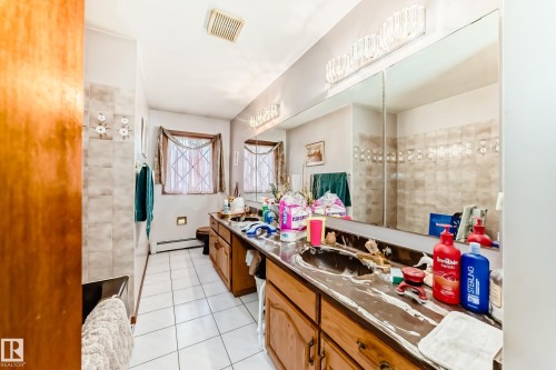 Bathroom featuring a double vanity with integrated sinks, a wall-mounted mirror, and overhead lighting fixtures - 208 Willow Crescent, Wetaskiwin, AB - Indoor Photo Showing Other Room