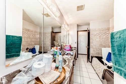 Bathroom featuring an extended vanity with dual sinks, a large wall-mounted mirror, and overhead vanity lighting - 208 Willow Crescent, Wetaskiwin, AB - Indoor