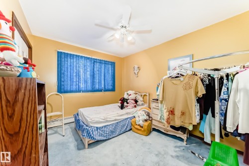 Bedroom featuring a ceiling fan with integrated lighting, wood-finish shelving unit, blue vertical blinds, and wall-to-wall carpeting - 208 Willow Crescent, Wetaskiwin, AB - Indoor Photo Showing Bedroom