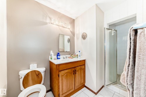 Bathroom featuring a wood vanity with a white countertop, chrome faucet, and rectangular mirror - 208 Willow Crescent, Wetaskiwin, AB - Indoor Photo Showing Bathroom