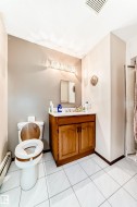 Bathroom featuring white square tile flooring, a wood-finish vanity with a white countertop, and a shower enclosure - 