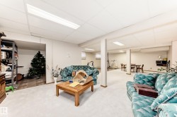 Spacious recreation room featuring carpet flooring, drop ceiling with integrated lighting, structural support columns, and an open layout providing versatile space - 