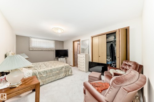 Carpeted room featuring a window with horizontal blinds, built-in bi-fold closet doors, and a flush-mount ceiling light fixture - 208 Willow Crescent, Wetaskiwin, AB - Indoor Photo Showing Bedroom