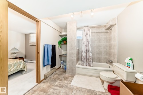 Bathroom featuring a tub/shower combination with tile surround, white toilet, and track lighting - 208 Willow Crescent, Wetaskiwin, AB - Indoor Photo Showing Bathroom