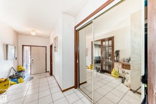 Entryway featuring white square tile flooring and a mirrored sliding closet door - 208 Willow Crescent, Wetaskiwin, AB - Indoor Photo Showing Other Room