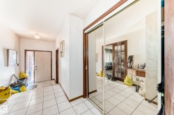Entryway featuring white square tile flooring and a mirrored sliding closet door - 