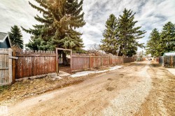Gravel alleyway running parallel to a wood privacy fence - 