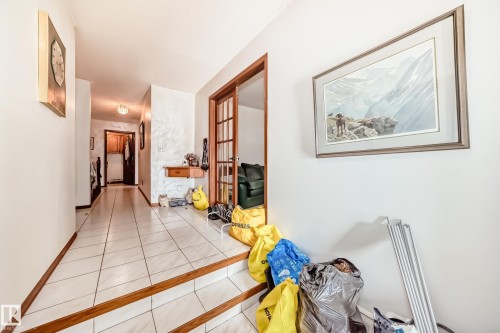 Hallway with light-toned tiled flooring, wood trim, and a built-in wall shelf - 208 Willow Crescent, Wetaskiwin, AB - Indoor Photo Showing Other Room