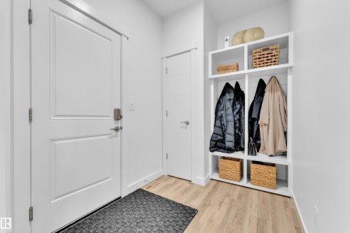 Entryway featuring light wood-style flooring, a white paneled door with a contemporary handle, and a built-in storage unit - 7815 174 Avenue, Edmonton, AB - Indoor Photo Showing Other Room