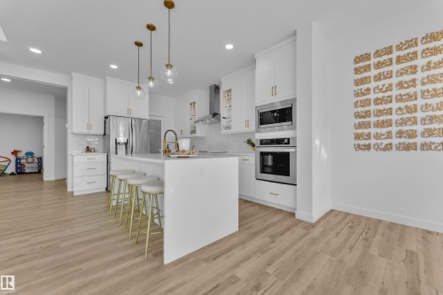 The kitchen features white cabinetry, stainless steel appliances, and an island with pendant lighting - 7815 174 Avenue, Edmonton, AB - Indoor Photo Showing Kitchen With Upgraded Kitchen