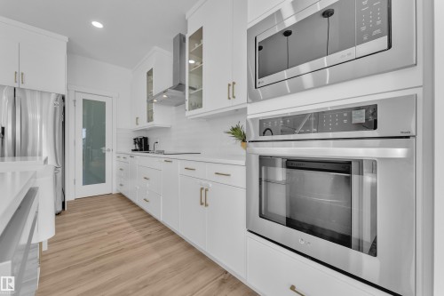 The kitchen features white cabinetry with gold-toned hardware, stainless steel appliances, and light-toned flooring - 7815 174 Avenue, Edmonton, AB - Indoor Photo Showing Kitchen