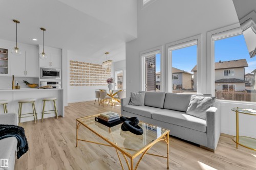 This open-concept living space features hardwood flooring and large windows providing ample natural light - 7815 174 Avenue, Edmonton, AB - Indoor