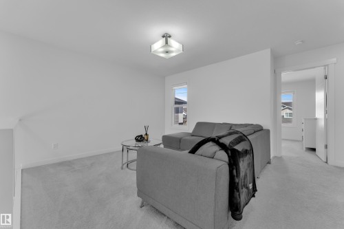 This living space features light gray carpeting, neutral white walls, and a modern ceiling light fixture - 7815 174 Avenue, Edmonton, AB - Indoor