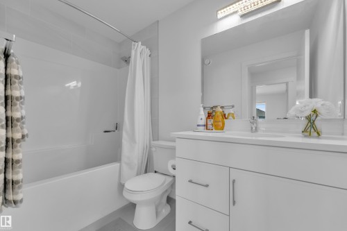 Bathroom featuring a white vanity with silver hardware, a large mirror, and a built-in bathtub with a shower - 7815 174 Avenue, Edmonton, AB - Indoor Photo Showing Bathroom