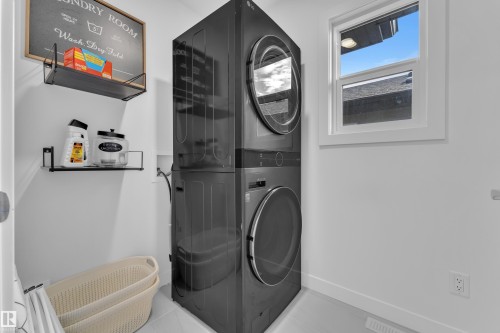 The laundry room features a stacked washer and dryer, open shelving, and a window providing natural light - 7815 174 Avenue, Edmonton, AB - Indoor Photo Showing Laundry Room