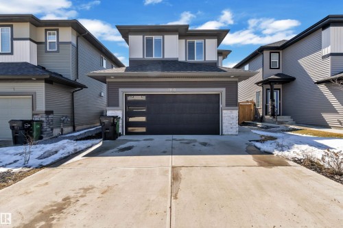 Contemporary architectural style property featuring a dark gray garage door with frosted glass accents, light gray siding, and a concrete driveway - 7815 174 Avenue, Edmonton, AB - Outdoor With Facade