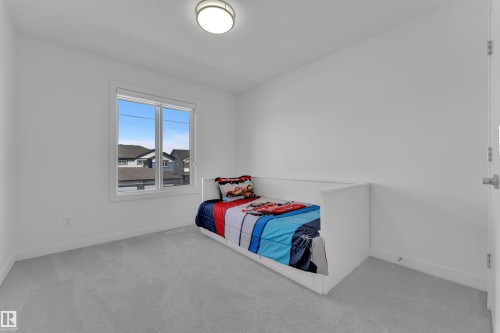 This room features light grey carpeting, a large window with white trim, and a white ceiling light fixture - 7815 174 Avenue, Edmonton, AB - Indoor Photo Showing Bedroom