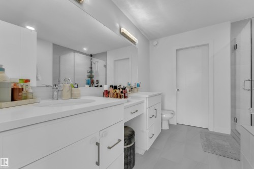 Bathroom featuring a double vanity with white cabinetry, a large mirror, and a glass-enclosed shower - 7815 174 Avenue, Edmonton, AB - Indoor Photo Showing Bathroom