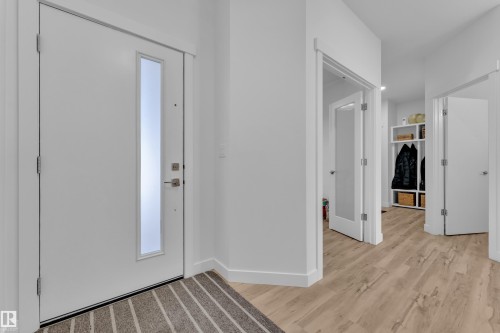 The entryway features a white door with a vertical frosted glass insert, leading to light-toned hardwood-style flooring - 7815 174 Avenue, Edmonton, AB - Indoor Photo Showing Other Room