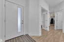 The entryway features a white door with a vertical frosted glass insert, leading to light-toned hardwood-style flooring - 7815 174 Avenue, Edmonton, AB  - Indoor Photo Showing Other Room 