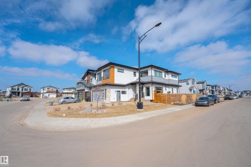 The property features a modern exterior with a mix of white and gray siding, accented by wood-toned panels - 3130 Kostash Green, Edmonton, AB - Outdoor With Facade