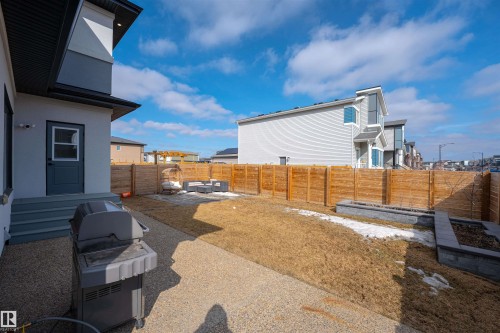 The property features a backyard with a wooden fence, a gravel patio area, and raised garden beds - 3130 Kostash Green, Edmonton, AB - Outdoor