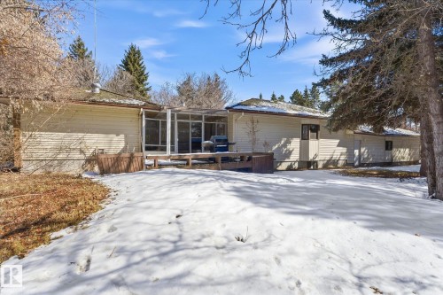 Rear exterior with a spacious wood deck, enclosed porch, and surrounding mature trees - 25750 18 Street, Edmonton, AB - Outdoor
