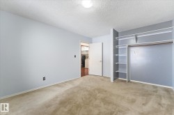 Room featuring light blue wall paint, textured ceiling, and neutral-toned carpeting - 