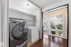 Dedicated laundry area featuring built-in shelving, overhead lighting, and wood-finish flooring - 