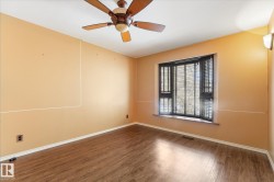 Room featuring wood-finish flooring, a ceiling fan, bay window with blinds, and wall sconce lighting - 