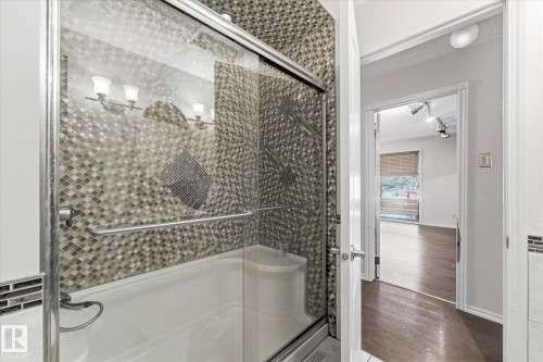 Tub-shower combination featuring sliding glass doors and mosaic tile surround - 25750 18 Street, Edmonton, AB - Indoor