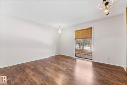 Room featuring wood-finish flooring, white walls, and a window with wood blinds - 