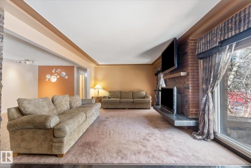 Living area featuring a brick fireplace with a slate hearth, large sliding glass doors, and a stone accent wall - 25750 18 Street, Edmonton, AB - Indoor Photo Showing Living Room With Fireplace