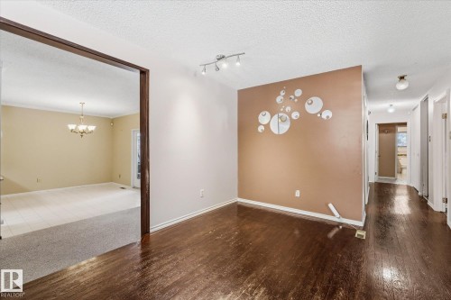 Rich wood-finish flooring extending through an open doorway to a room with light-colored tile and carpet - 25750 18 Street, Edmonton, AB - Indoor Photo Showing Other Room