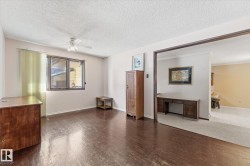 Room featuring dark wood-finish flooring, a window with vertical blinds, and a ceiling fan - 