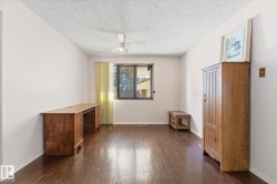 Spacious room featuring wood-finish flooring, light-toned wall paint, and a window with vertical blinds - 