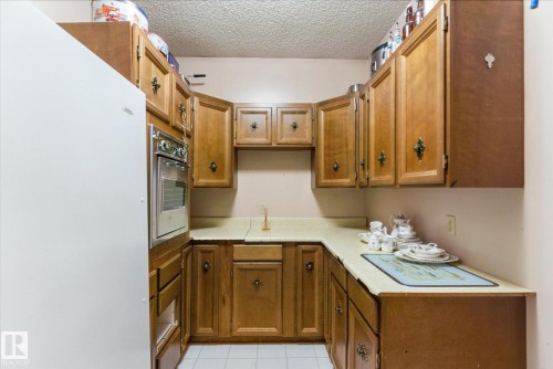 U-shaped kitchen with wood cabinetry and light-colored countertops - 25750 18 Street, Edmonton, AB - Indoor Photo Showing Kitchen