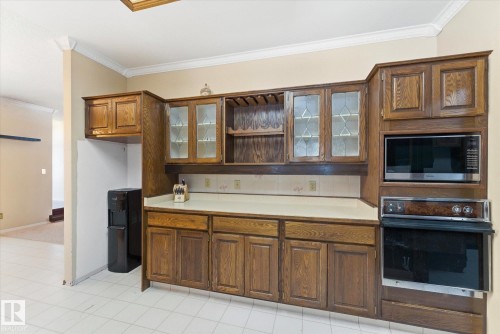 Kitchen cabinetry with glass-front display cabinets, integrated wine rack, built-in microwave, and wall oven - 25750 18 Street, Edmonton, AB - Indoor Photo Showing Kitchen