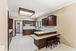 Kitchen featuring extensive dark wood cabinetry, light-toned countertops, and a built-in breakfast bar - 