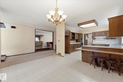 Spacious kitchen and dining area featuring wood-finish cabinetry, white tile flooring, and a breakfast bar - 