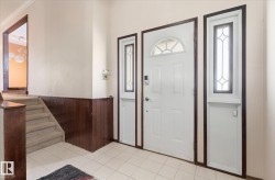 Entryway featuring a white paneled door with an arched transom, flanked by two sidelights with decorative grilles - 