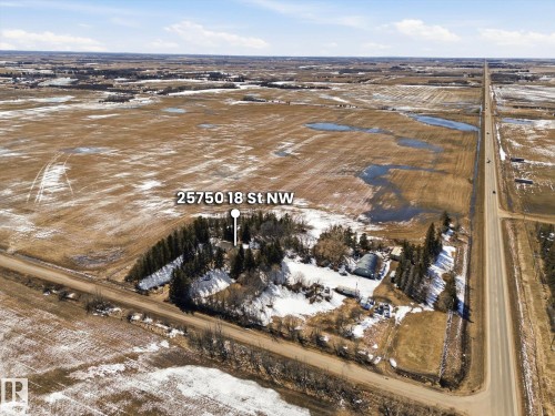 Aerial property overview featuring a main residence, multiple outbuildings, mature tree lines, and expansive surrounding acreage - 25750 18 Street, Edmonton, AB - Outdoor With View