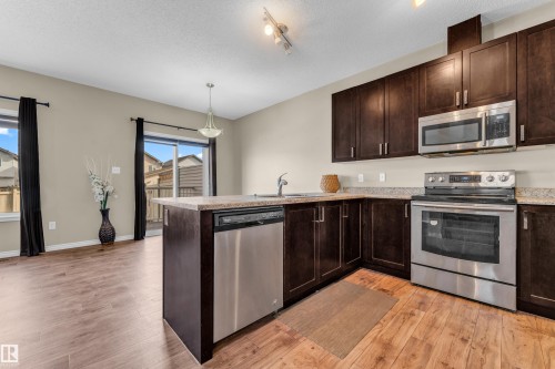 Kitchen featuring dark wood-finish cabinetry, stainless steel appliances, and a light-toned countertop - 2526 19A Avenue, Edmonton, AB - Indoor Photo Showing Kitchen With Stainless Steel Kitchen