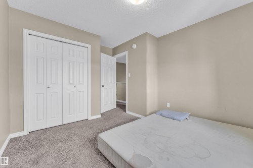 Neutral-toned room with textured carpeting, white baseboards, and a bi-fold closet with panel detailing - 2526 19A Avenue, Edmonton, AB - Indoor Photo Showing Bedroom