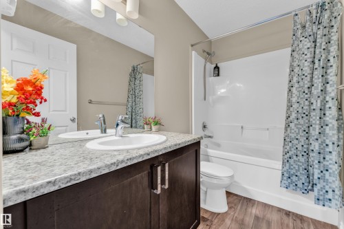Bathroom featuring a dark wood-finish vanity with a light speckled countertop, dual undermount sinks, and chrome faucets - 2526 19A Avenue, Edmonton, AB - Indoor Photo Showing Bathroom