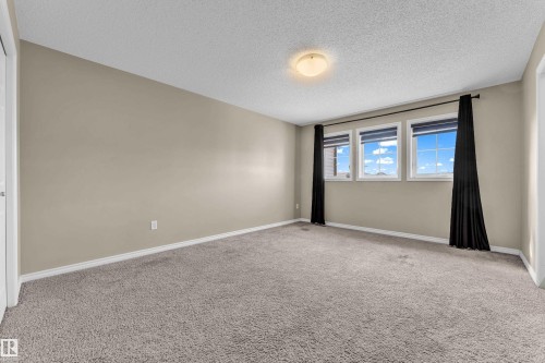 Spacious room featuring neutral carpeting, a trio of windows, and a flush-mount ceiling light fixture - 2526 19A Avenue, Edmonton, AB - Indoor Photo Showing Other Room